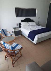 a bedroom with a bed and a chair and a table at Surf Point Ride in Jeffreys Bay