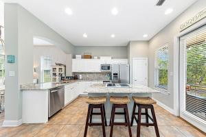 Una cocina con gabinetes blancos y una encimera con taburetes. en Casa Playa, en Gulf Highlands
