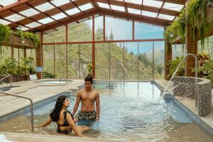 a man and a woman sitting in a swimming pool at Casa Augusto en El Refugio Spa Garden in Baños