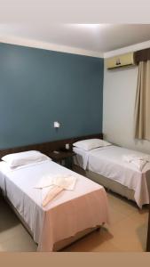 two beds in a room with blue walls at Veneza Plaza Hotel in Gurupi +12 photos