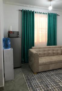 a living room with a couch and green curtains at Bliss Residence Bamburi Mwembeni in Mombasa