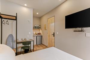 a bedroom with a bed and a desk and a tv at Allende By Homirent in Querétaro