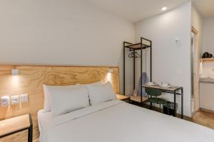 a bedroom with a large white bed and a desk at Allende By Homirent in Querétaro
