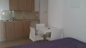 una cocina con mesa y 2 sillas y una cocina con fregadero en Simos Magic Hotel Apts, en Ayia Napa