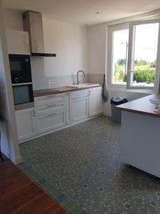 une cuisine avec des placards blancs et une grande fenêtre dans l'établissement GITE chez mamie - 7 personnes A SAINTE LIVRADE SUR LOT, à Sainte-Livrade-sur-Lot
