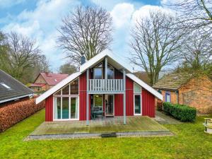 a red house with a white roof on a yard at Ferienhaus mit Terrasse und Balkon in Granzow