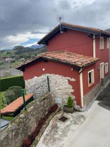 a red house with a stone wall at Vivienda Vacaional El Navariegu 2 in Garaña