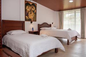 a bedroom with two beds and a painting on the wall at Casa Augusto en El Refugio Spa Garden in Baños