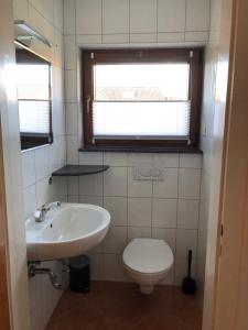 a bathroom with a sink and a toilet and a window at Meldorf-Ferienhaus in Meldorf +7 photos