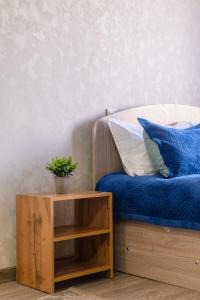 Una cama con sábanas azules y una mesa con una maceta. en One Bedroom Apartment Next to Arbat In The Golden Square, en Almaty
