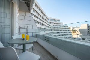 a balcony with a table and chairs and a building at סוויטה Twins בוטיק עם נוף וצמודה לים במתחם SeaSide היוקרתי עם בריכה - By SEAELO EILAT in Eilat