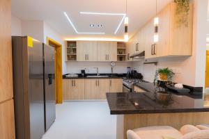 a kitchen with wooden cabinets and a black counter top at Modern 3BR! 9FL, King Bed! STI with Pool! Fast wifi! in Santiago de los Caballeros