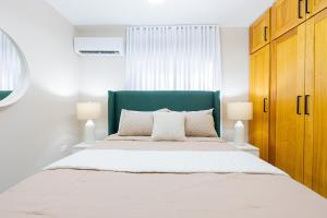 a bedroom with a large bed with a green headboard at Modern 3BR! 9FL, King Bed! STI with Pool! Fast wifi! in Santiago de los Caballeros +71 photos