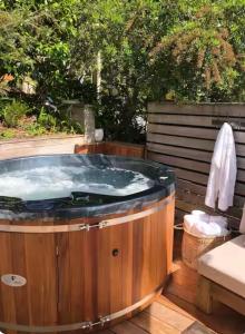 a hot tub on a wooden deck with a bench at Villa Del Mar Seaside Escape in Orewa +32 photos