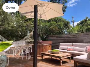 a hammock and an umbrella on a patio at Villa Del Mar Seaside Escape in Orewa