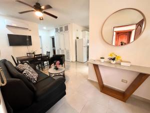 sala de estar con sofá negro y espejo en Cozy Condo - 4 min to the Beach, en Punta Cana