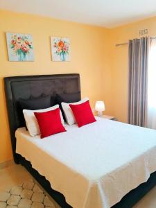 a bedroom with a large bed with two red pillows at Jacobi Apartments in Kitwe +6 photos