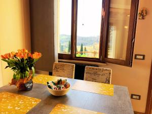 a dining room table with a vase of flowers and a window at Casale SoleLuna - Bagno condiviso in Sorrezzana