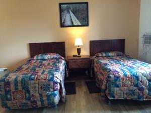 two beds in a room with two lamps on at Carleton Motel and Coffee Shop in Borden-Carleton