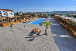 a resort with a pool with lounge chairs and a palm tree at Mobillehome Camp Turanj in Turanj