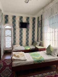 a bedroom with two beds and a window at Abdurauf in Bukhara