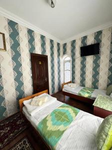 two beds in a room with blue and white wallpaper at Abdurauf in Bukhara