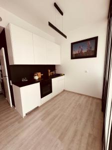 una cucina con mobili bianchi e pavimento in legno di Hanza Tower, Apartament LESS IS MORE 15TH basen Sauna Spa a Stettino