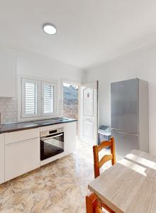 Una cocina con gabinetes blancos y una mesa y un refrigerador. en Apartamento Relax 2, en Las Palmas de Gran Canaria