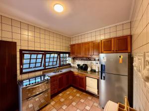 une cuisine avec des armoires en bois et un réfrigérateur en acier inoxydable dans l'établissement Casa 10 Pessoas Riviera de São Lourenço, à Bertioga