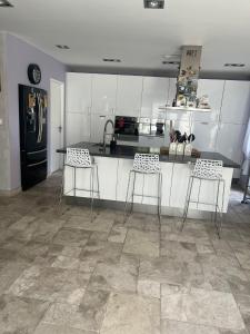 a kitchen with white cabinets and a counter with stools at BELLE VILLA 8 à 10 personnes parc du verdon in La Verdière