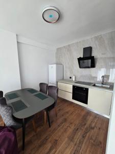La cuisine est équipée d'une table, d'un évier et d'un réfrigérateur. dans l'établissement INA Apartment Oasis 2, à Pristina
