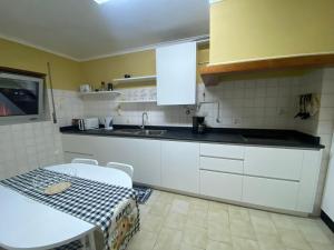 eine Küche mit weißen Schränken und einem Tisch und einer Spüle in der Unterkunft A Terraza da Filipa in Vila Praia de Âncora + 48 Fotos
