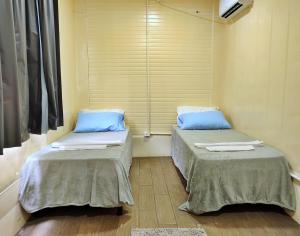 two twin beds in a room with a window at Hotel Tucano in Inocência +4 photos