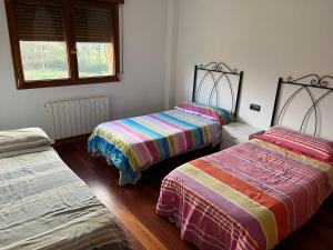 una habitación con dos camas y dos ventanas en Casa independiente, en Liendo