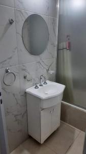 een witte badkamer met een wastafel en een spiegel bij Solano House in Termas de Río Hondo