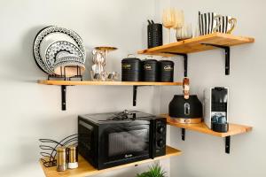 a microwave on a wall with wooden shelves at One Apartments TLV in Tel Aviv +133 photos