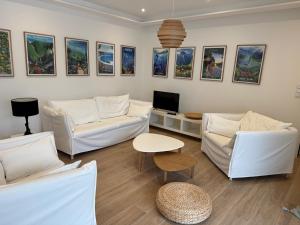 a living room with white couches and a tv at Maison Trégastel, proche plage Coz Pors in Trégastel
