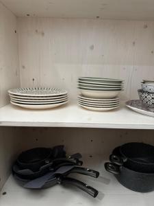 a shelf with plates and bowls and utensils on it at Aethera in Revine Lago