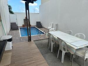 a table and chairs next to a swimming pool at Triplex Completo em Pitimbu - PB in Pitimbu
