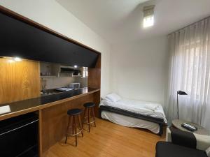 een kleine kamer met een bed en een bureau met krukken bij Apart Hotel Guignard 305 - Moderno e Acolhedor in Belo Horizonte