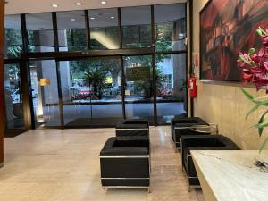 een lobby met zwarte stoelen en een gebouw met ramen bij Apart Hotel Guignard 305 - Moderno e Acolhedor in Belo Horizonte