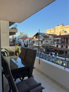 a balcony with a table and chairs and a view of a city at Mnēmes Apartment in Neoi Epivates