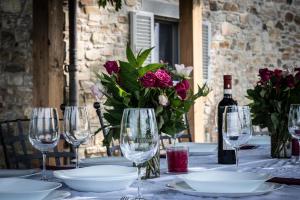 a table with glasses and a bottle of wine and flowers at Villa Casale Chiesina in Bibbiena