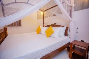 a bedroom with a bed with white sheets and yellow pillows at SHD Paddy Villa in Talpe