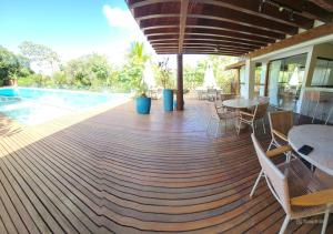 a wooden deck with tables and chairs next to a pool at Casa em Praia do Forte Refúgio Luxo e Natureza in Praia do Forte