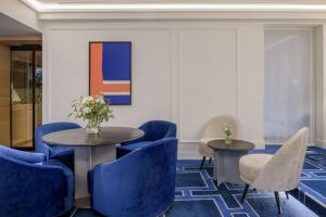 a lobby with blue chairs and tables and a painting at El Autor Hotel, Madrid, Autograph Collection in Madrid