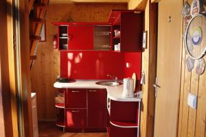uma pequena cozinha com armários vermelhos e um lavatório em The Jolly Man em Vilnius