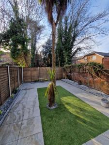 un palmier dans une cour à côté d'une clôture dans l'établissement Stylish 3 bed 3 ensuites house with parking & garden, à Reading