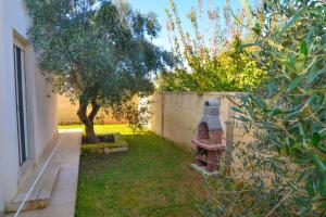 a garden with a brick wall and a tree at Boomerang Village 4 Stars in Torre Colimena