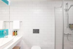 un bagno bianco con doccia e lavandino di Holiday Inn Express & Suites Sion by IHG a Sion Altre 37 foto